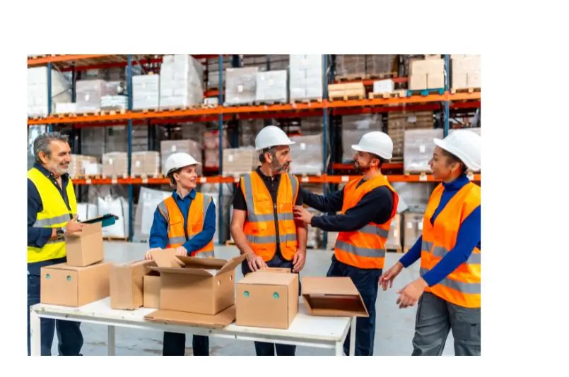 Profesionales en un almacén preparando pedidos y coordinando tareas de trabajo en logística.